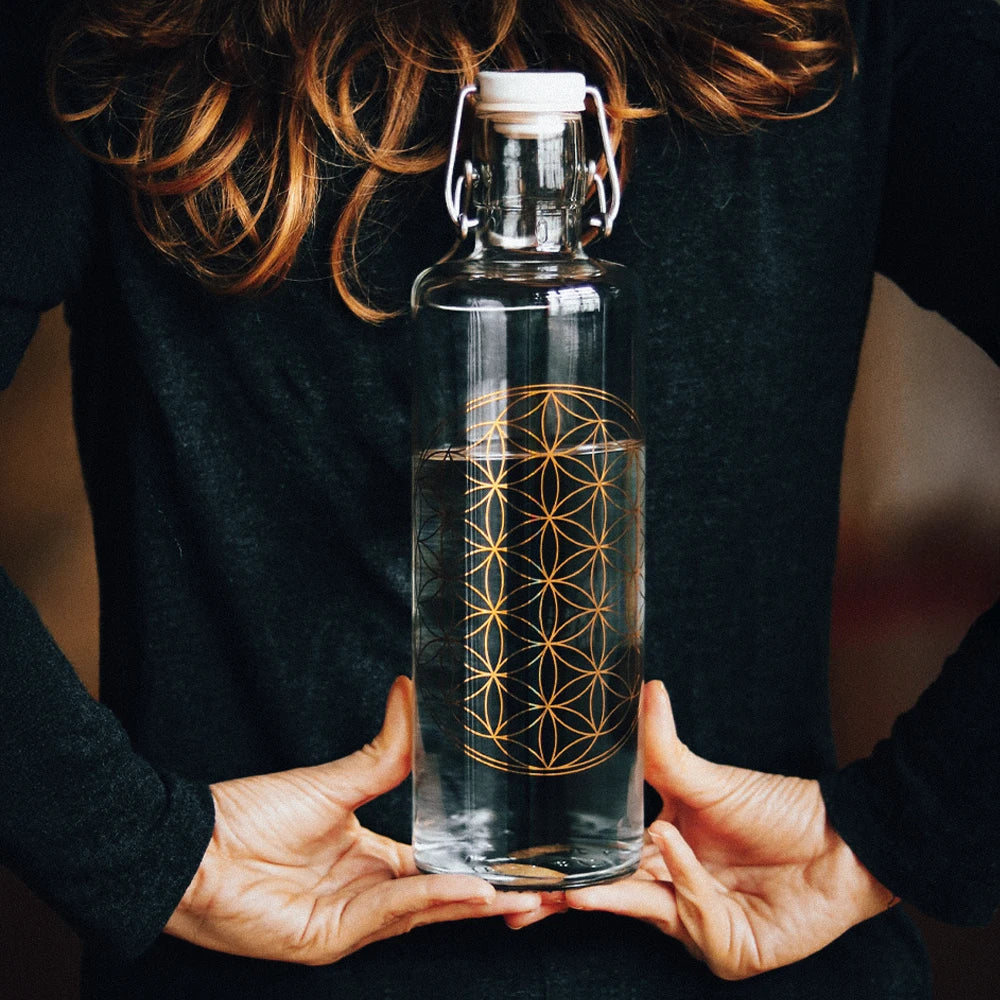 Frau mit Trinkflasche hinter dem Rücken mit Blume des Lebens Motiv